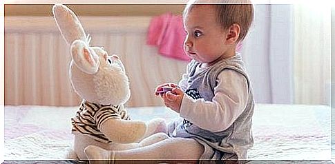 Baby is playing with a plush bunny.