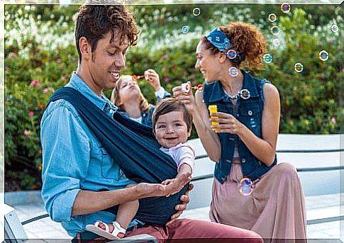 Father and mother with child in baby carrier